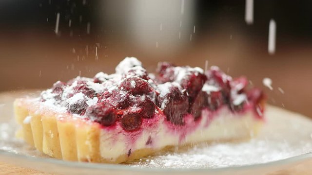 Sprinkle sugar powder on rotating cheesecake slow motion. Close up shot on 4k RED camera