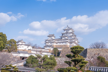 Himeji old defence stone wall with architectural castle complex on hill with floating white clouds casting shadows