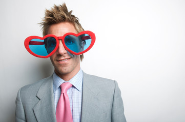 Businessman with oversize red heart glasses smiling with wide eyes
