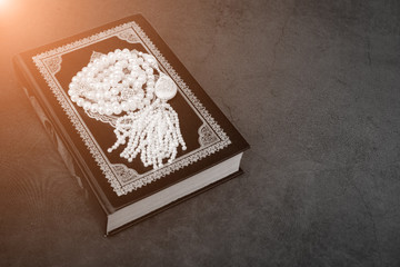 Muslim islamic faith concept Koran book , white rosary with the inscription Allah . gray dark...