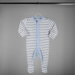 Blue striped clothes for a newborn hanging on a hanger. The concept of clothes, motherhood and newborn.