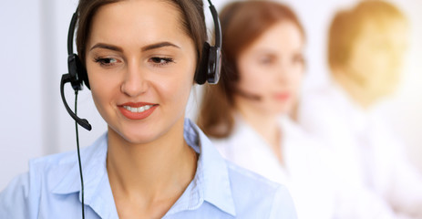 Call center. Focus on beautiful business woman using headset in sunny office