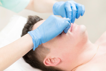 Cosmetic procedure for applying a therapeutic mask to a young man in a beauty salon.
