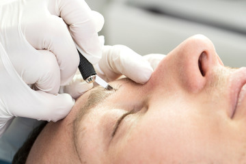 Obraz na płótnie Canvas Male microblading procedure to improve the condition of a man’s eyebrows in a beauty salon.