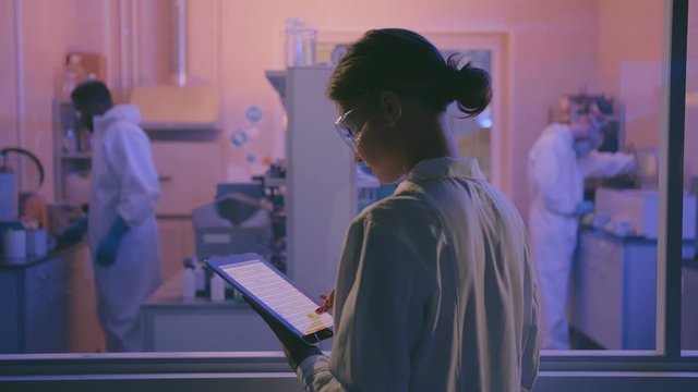 Female senior scientist with laptop managing medical project supervising her team.