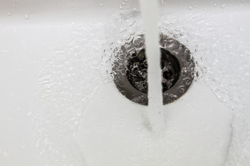 Water flows into the hole of the kitchen or bathroom sink. The concept of saving water