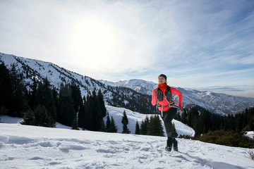 Trail runner woman running in winter mountains on snow. Dynamic running uphill on trail woman athlete runner side view