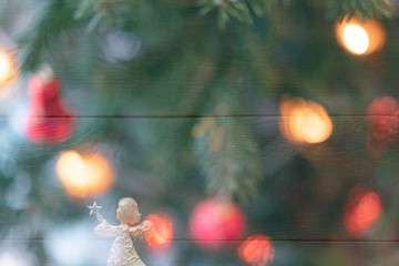 Christmas celebration card with a golden angel in front of a green background and surrounded by various colourful christmas lights