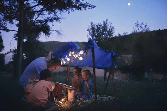Father with children playing under their backyard tent.
