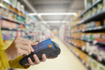 Female hand doing purchase through payment machine on store background