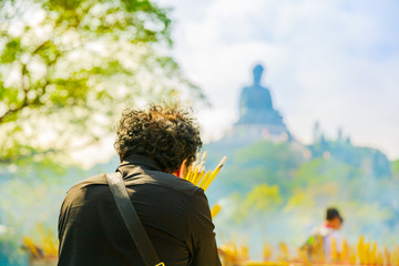 faithful people from behind preying with incense smoke the Big Buddha statue in China.