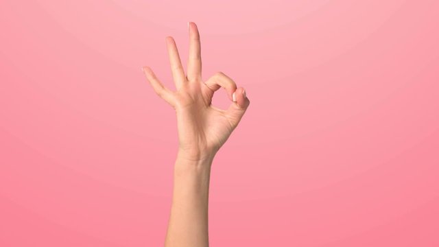 The girl raises her fist and shows the OK sign. A woman's hand shows the sign all is well