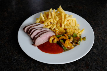 roasted fillet from red deer calf with french fries and yellow and green paprika