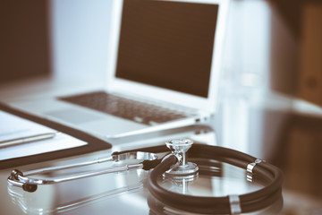 Stethoscope, prescription medical form lying on glass table with laptop computer. Medicine or pharmacy concept. Medical tools at doctor working table