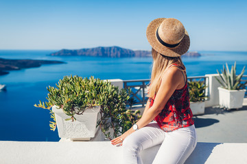 Fototapeta premium Woman traveler looking at Caldera landscape from Thera, Santorini island, Greece. Tourism, traveling, vacation