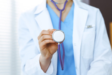 Unknown doctor woman holds stethoscope head, close-up. Physician ready to examine and help patient. Helping and insurance in health care, best treatment and medicine concept