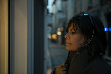 Obraz premium Woman Watching a Store Window at Night in Antibes, France.