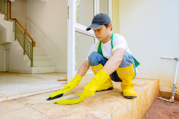 Asian cleaner using brush and shovel sweep dirt on floor