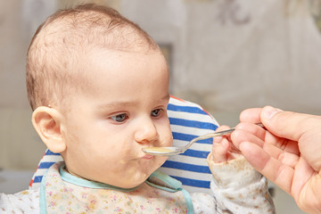 cute adorable baby eating porridge with a spoonful of the concept of proper nutrition