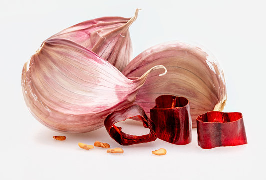Group of red garlic cloves and portions of hot chili pepper. Isolated on white background.