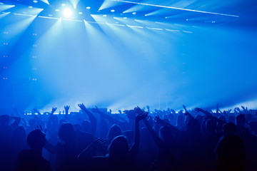 Happy people enjoying rock concert, raised up hands and clapping of pleasure.