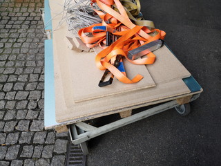 Plattformwagen mit Rollen und Spanplatten auf Kopfsteinpflaster mit Spanngurten in Orange für den...