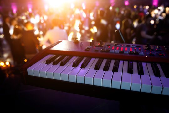 Piano keys in purple light on concert stage. Synthesizer.