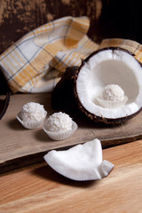 Coconut with white pulp and white candies on wooden background..