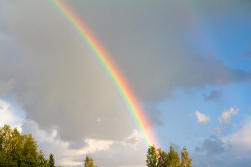 Rainbow against a background of blue sky and dark clouds