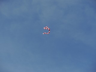 String of red and white balloons flying in the blue skies, wide shot