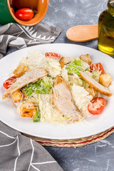 Caesar salad with chicken on a white plate. Shot in the decor