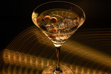 Long exposure martini glass with ice and olives