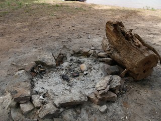 Ring of stones with embers and ashes from a bonfire by the side of a lake