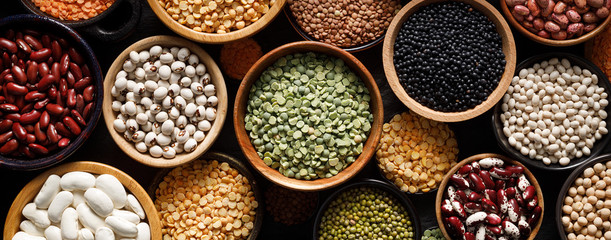 Legumes, a set consisting of different types of beans, lentils and peas on a black background, top view, close up. The concept of healthy and nutritious food