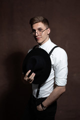 Man in round glasses, suspenders, a white shirt and a hat.