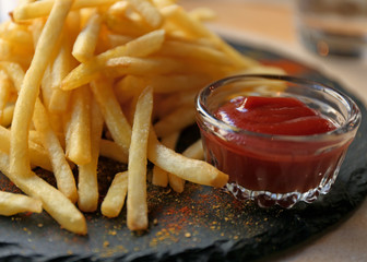 Tasty French fries with red sauce served on table in cafe, closeup