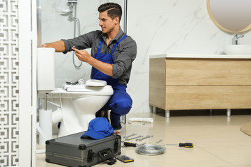 Professional plumber working with toilet bowl in bathroom - obrazy, fototapety, plakaty
