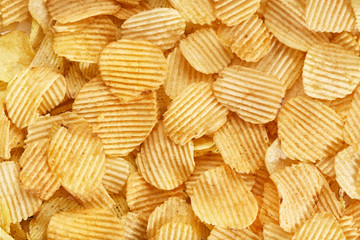 Potato grooved chips close up. Background of golden wavy corrugated chips  slices.