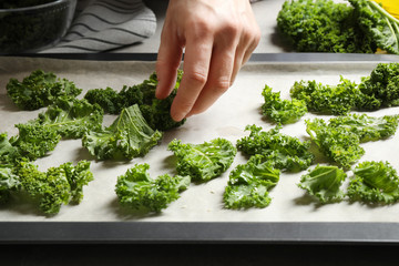 Woman preparing kale chips at table, closeup