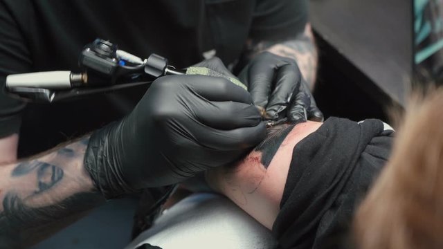 Footage of professional getting tattoo of snake in studio