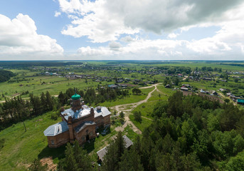 Church near the forest in Kaygorodskoe village, Russia, Sverdlovsk region. Aerial, summer, sunny