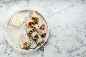 Delicious rolls wrapped in rice paper served on marble table, top view. Space for text