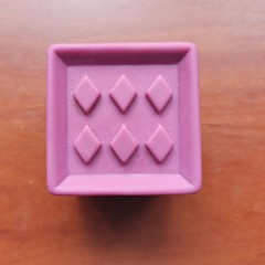 Purple toy cube with rhombus on wooden background