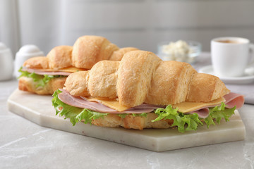 Tasty croissant sandwiches with ham on grey kitchen table