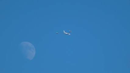 Poseidon P-8 Aircraft with military jet fighter escorts flying by the moon as they arrive in Scotland