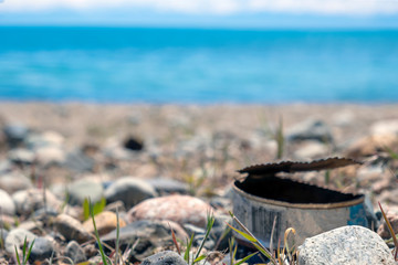 Garbage on the beach. Old tin is rusting on the beach. Blurred. Unfocused. Enviroment pollution.