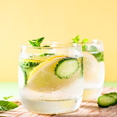 Healthy refreshing summer cocktail or mocktail without alcohol with lemon and cucumber. Summer detox drink on fresh green background, healthy living, top view