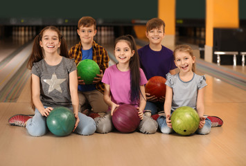 Happy children with balls in bowling club