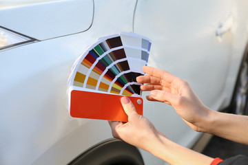 Woman with palette samples choosing color for painting car, closeup
