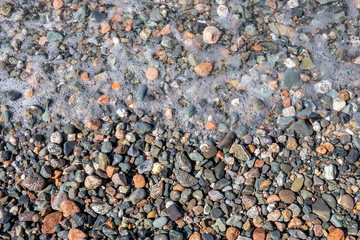Pebble beach with sea foam and bubbles background.